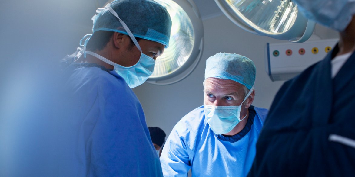 Two male healthcare providers in an operating room setting. Two male healthcare providers in an operating room setting.