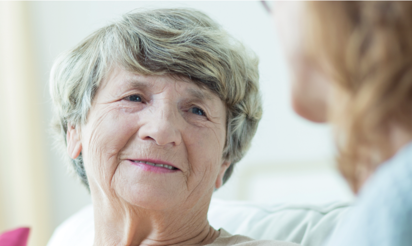 Elderly woman smiling in conversation with another woman