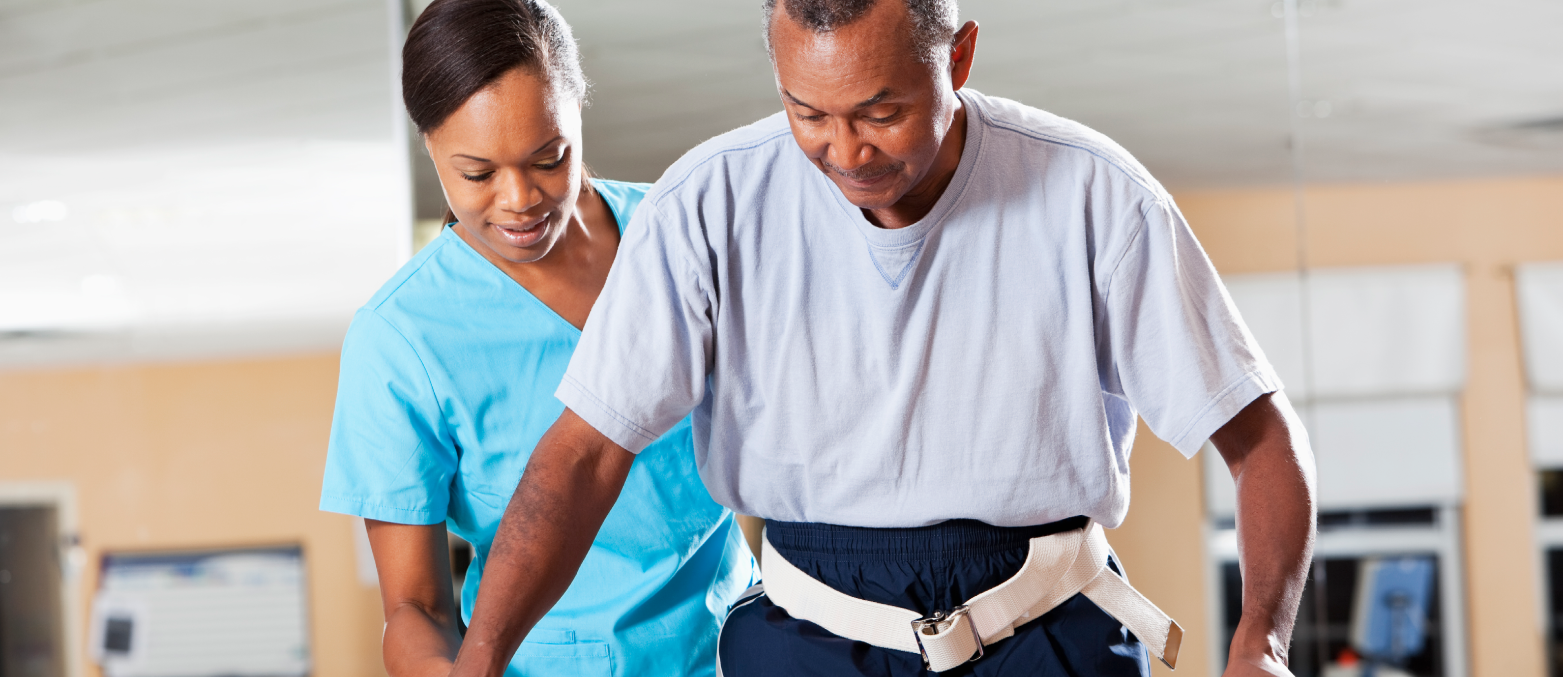 Healthcare provider assisting patient to walk through rehabilitation.